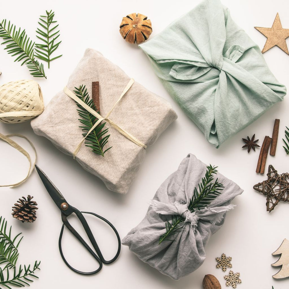 Hero image featuring a top down view of sustainably gift wrapped presents surrounded by holiday decor.