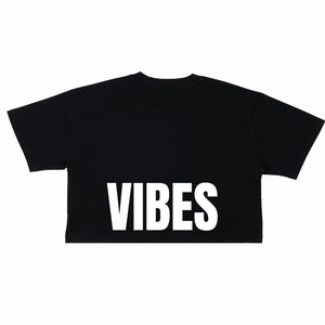 Image features the back of the Be Kind Vibes Be Kind crop top in black with the word Vibes printed in white just above the bottom seam