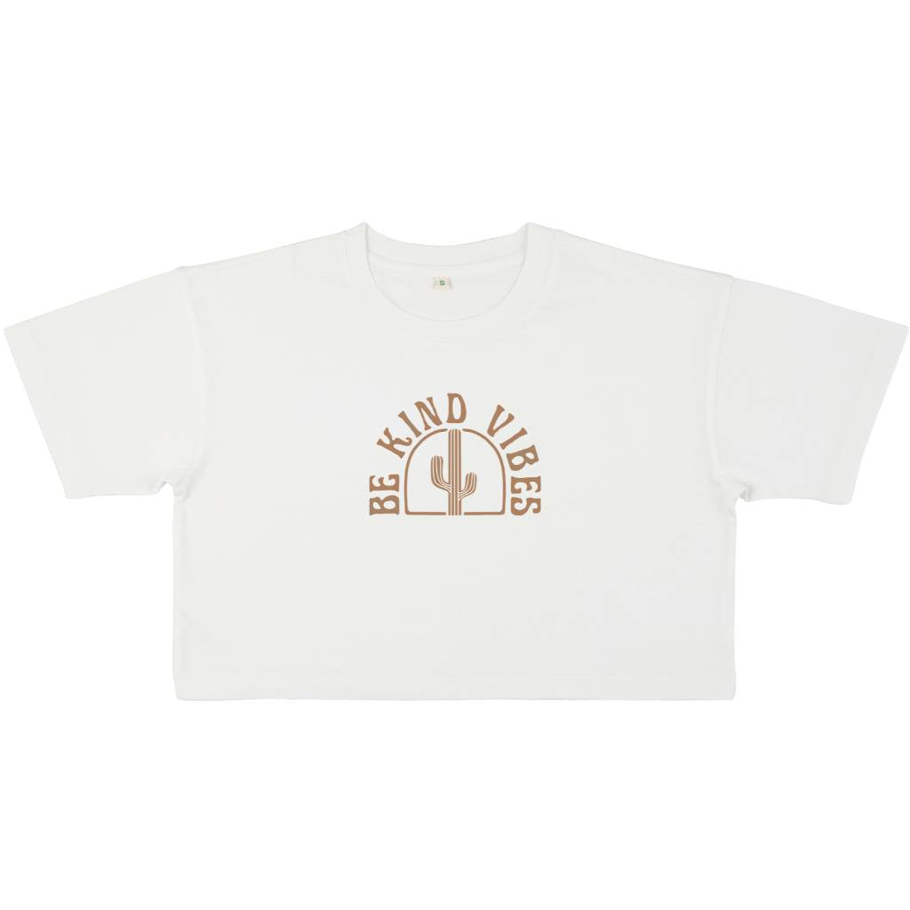 Image features the front of the Be Kind Vibes Desert Waves crop top on in stone wash white on a white background. The logo features a cactus with the text Be Kind Vibes written in a half circle over the top of the cactus.