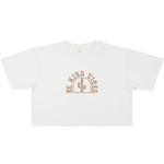 Image features the front of the Be Kind Vibes Desert Waves crop top on in stone wash white on a white background. The logo features a cactus with the text Be Kind Vibes written in a half circle over the top of the cactus.