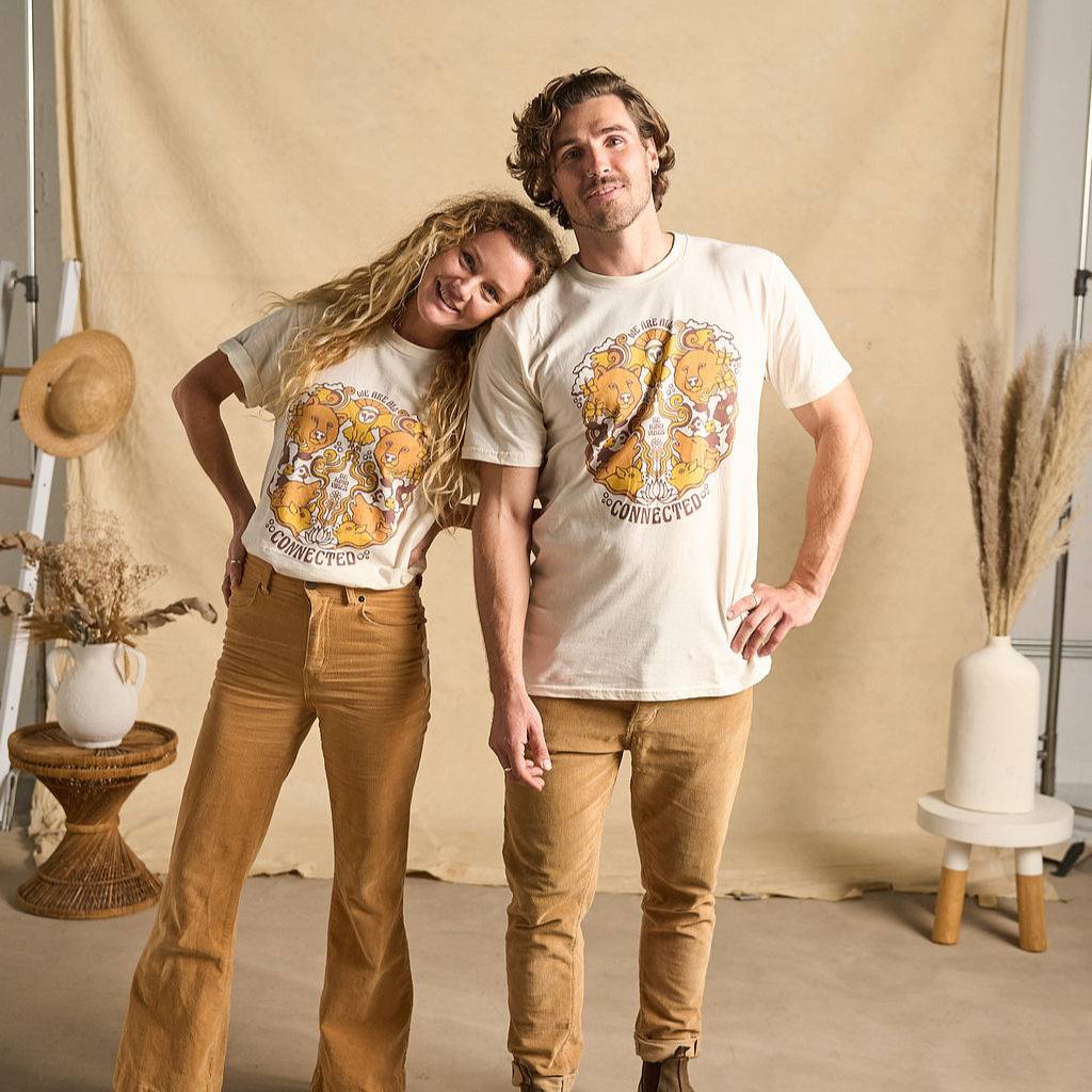 
                  
                    Image features a male and female standing in front of a beige colored fabric back drop wearing light brown colored khaki pants and the Be Kind Vibes We Are All Connected t-shirt that features an animal design on the front which includes bears, an owl, cows, pigs, chickens, and wolves.
                  
                