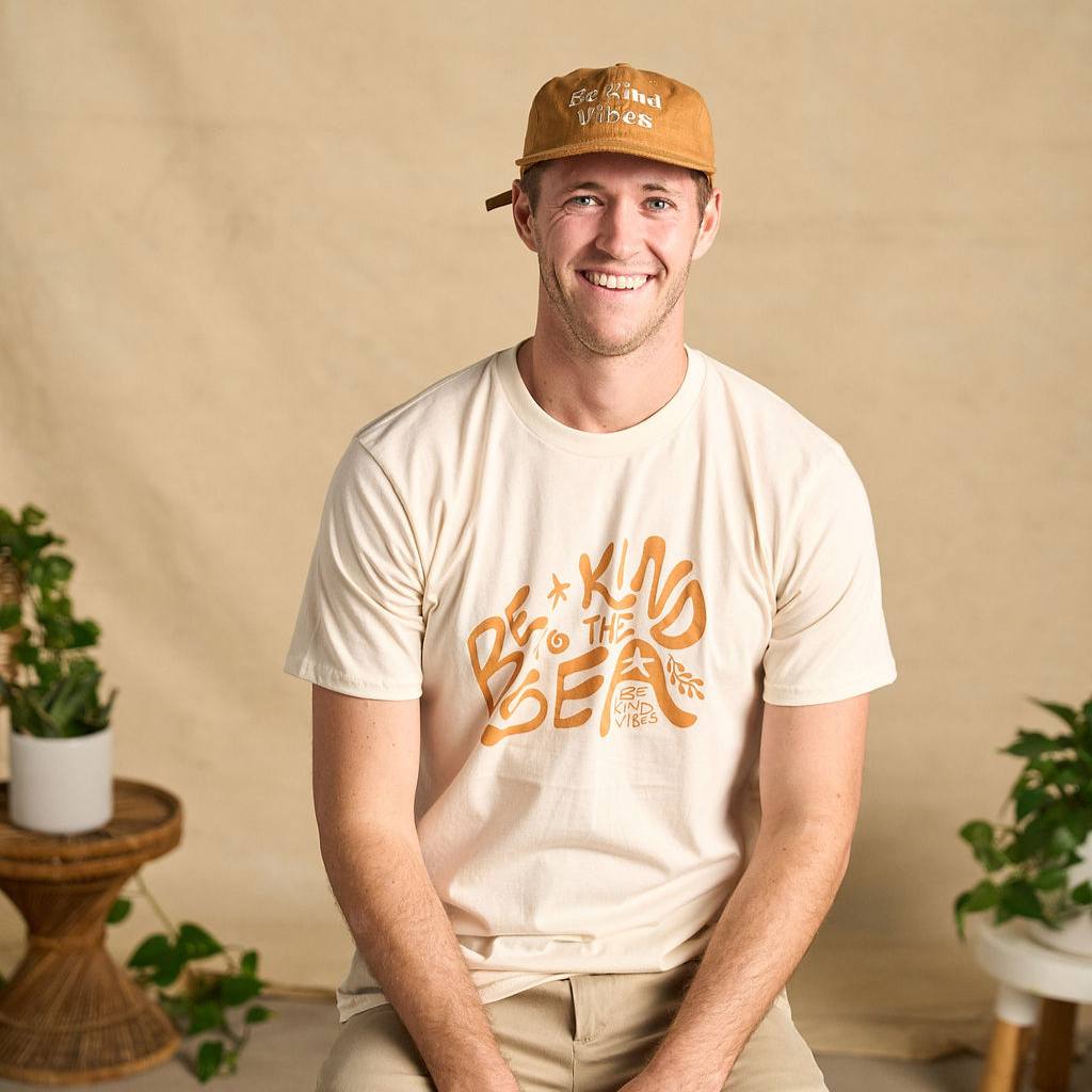 
                  
                    Image features a male model sitting on a stool with plants in the background wearing the rust colored Be Kind Vibes Be Kind Hemp hat, khaki pants, and the Be Kind Vibes Be Kind to the Sea organic cotton t-shirt in a natural colorway.
                  
                